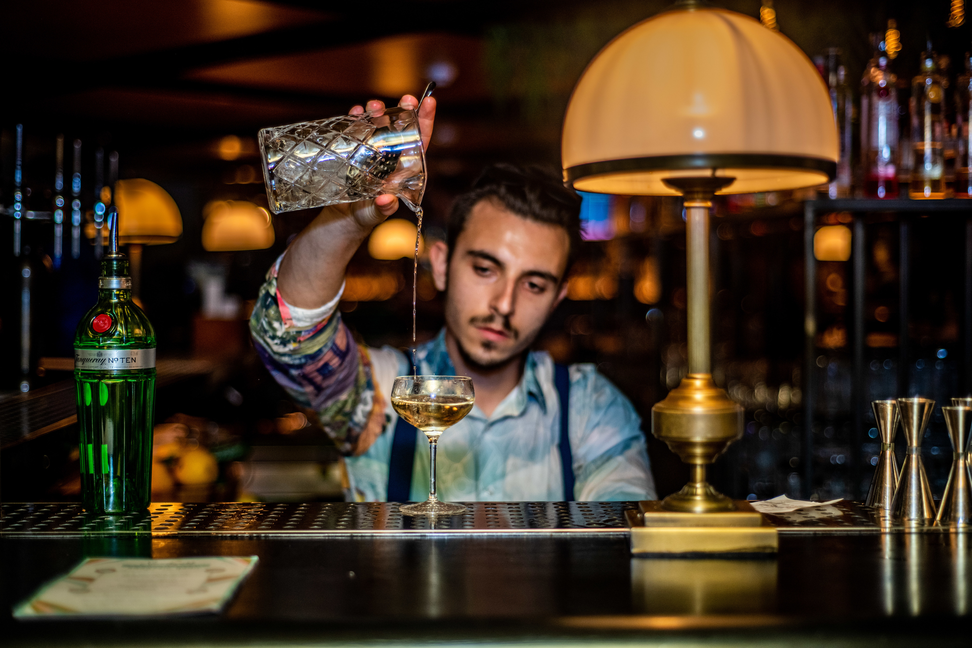 Bartender straining cocktail into cocktail glass